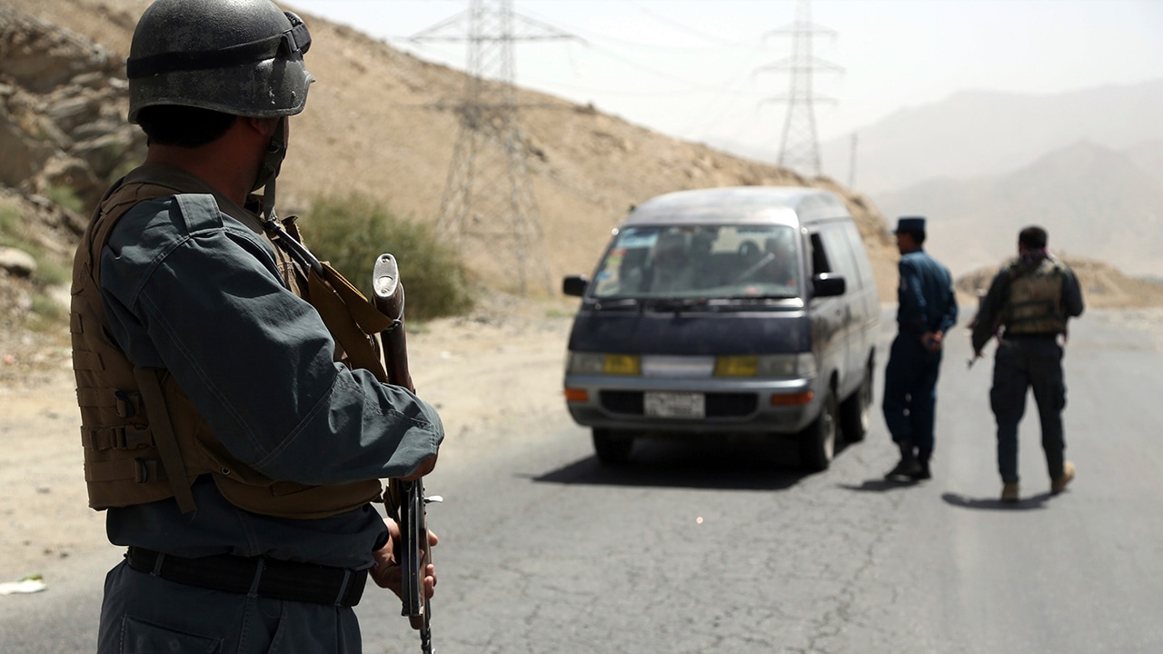 Photo of Afghan police officers searching a vehicle at a checkpoint on the Ghazni highway