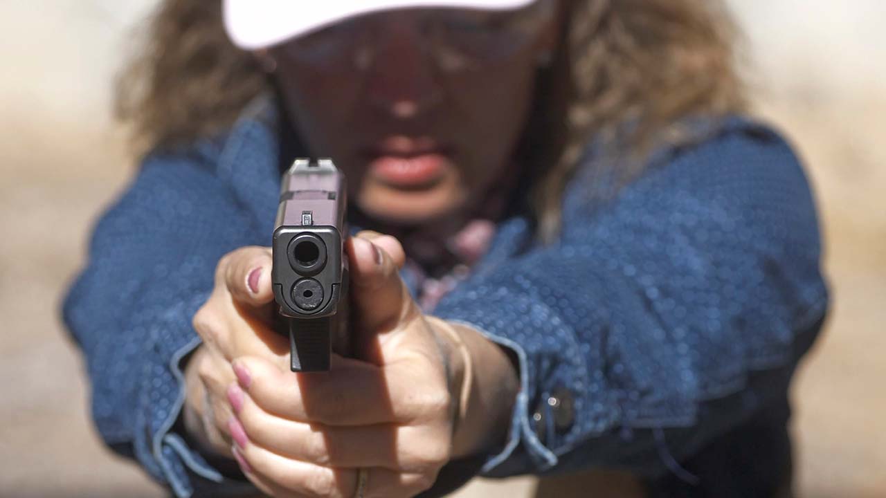 Photo of school secretary aiming a pistol at a shooting range