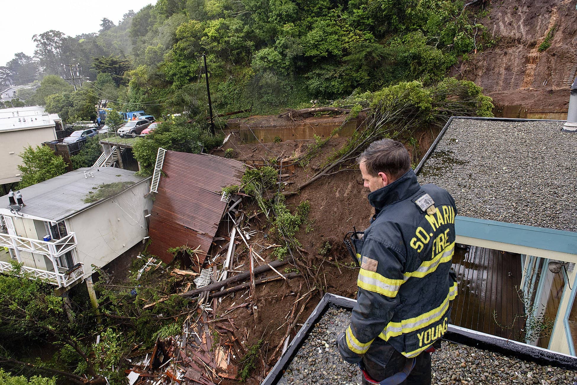 Photo of firefighter looking at wreckage caused by mudslide in California