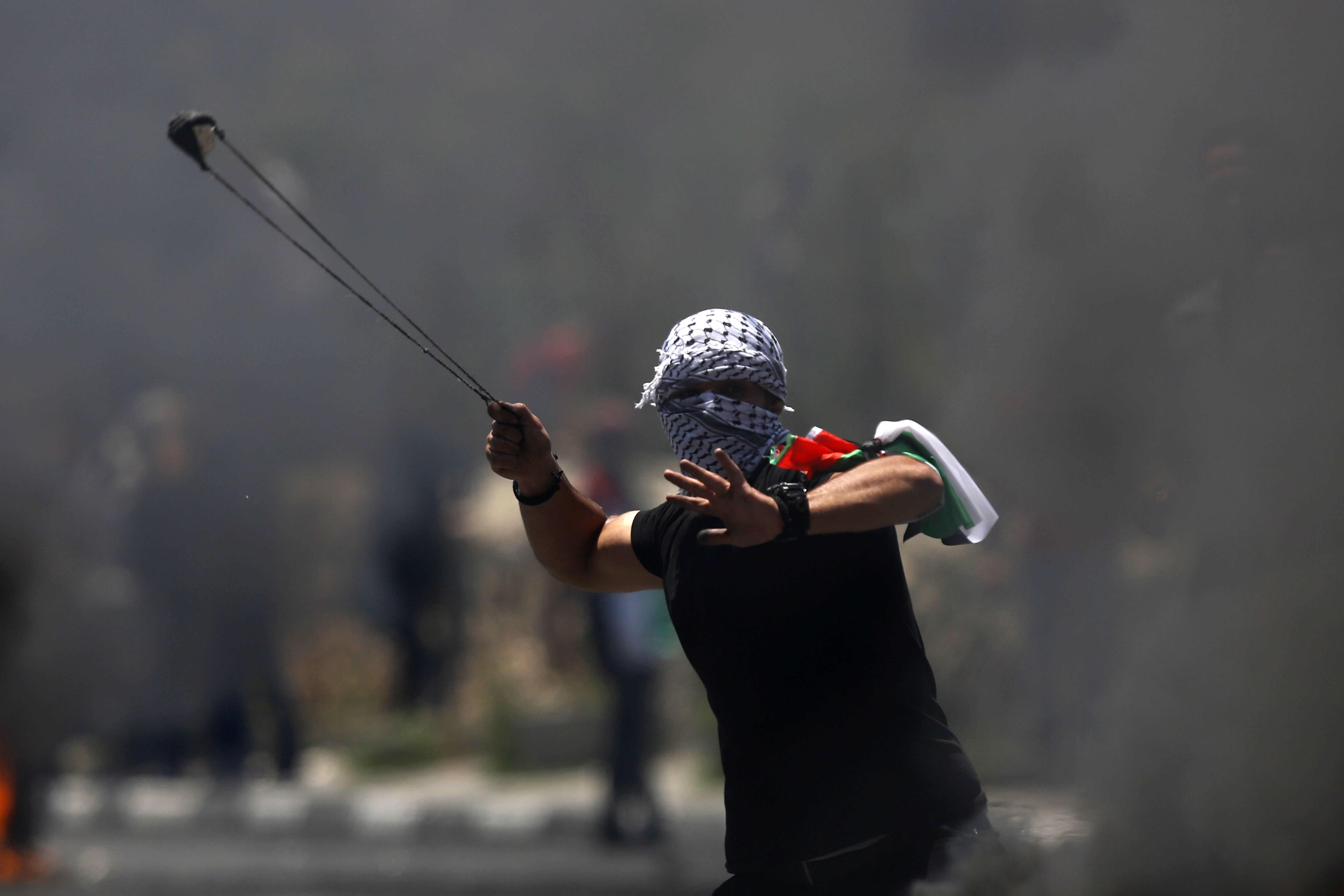 A Palestinian protester hurls a stone during clashes with Israeli forces after a rally to mark the 70th anniversary of what Palestinians call their "nakba."