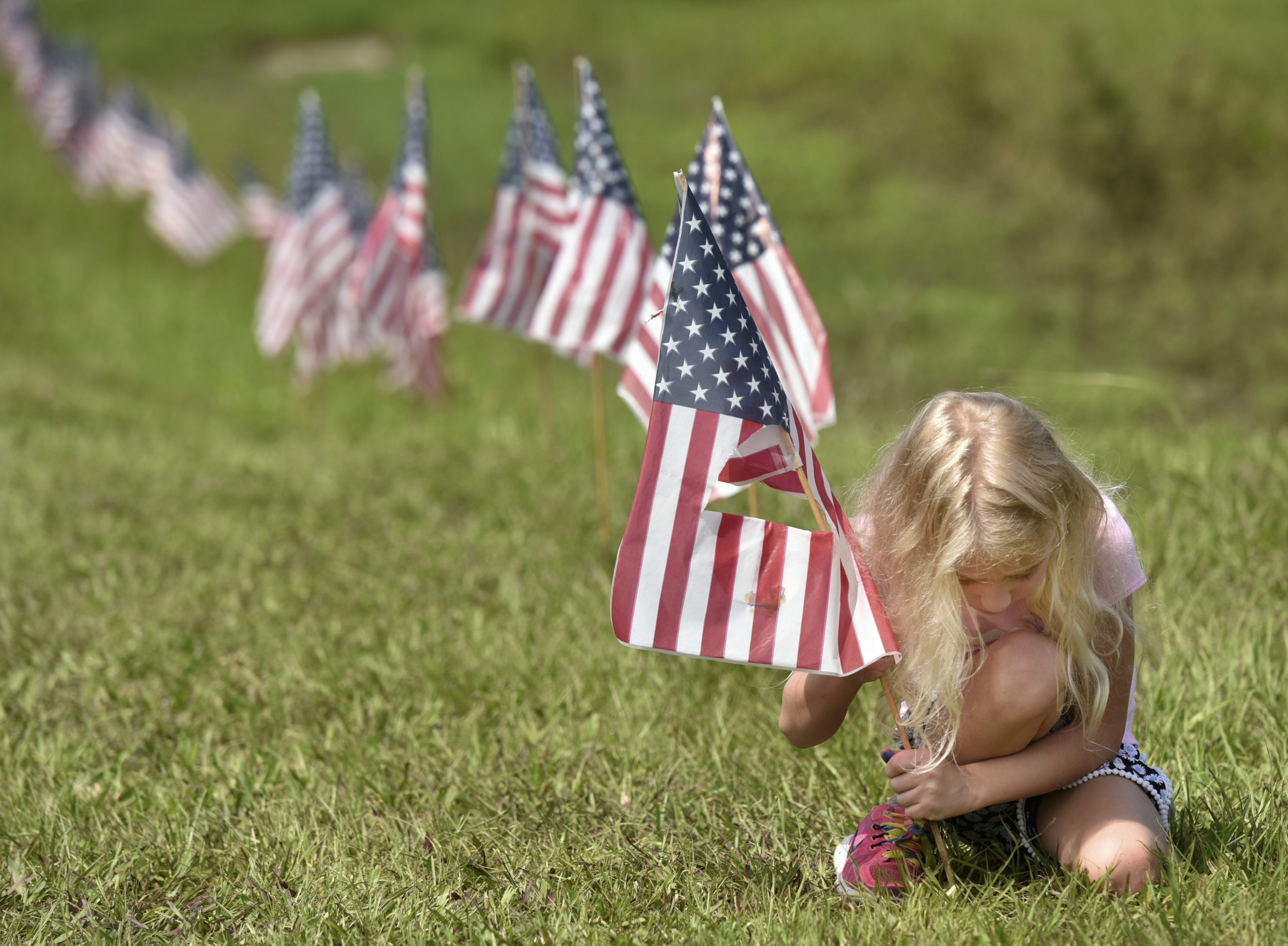 AP photo of a young girl putting American flags into the ground