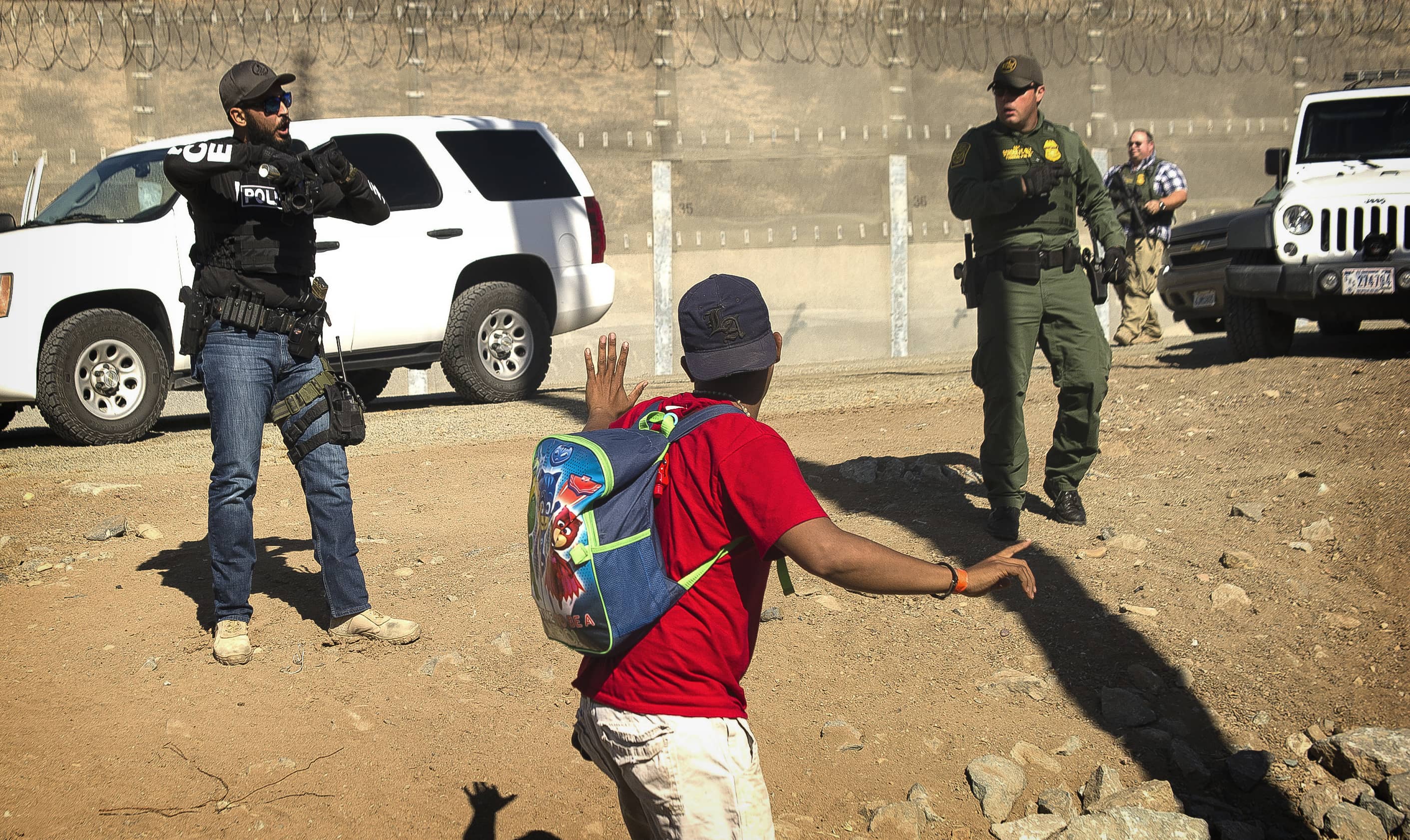 Photo of a migrant being stopped by border patrol agents