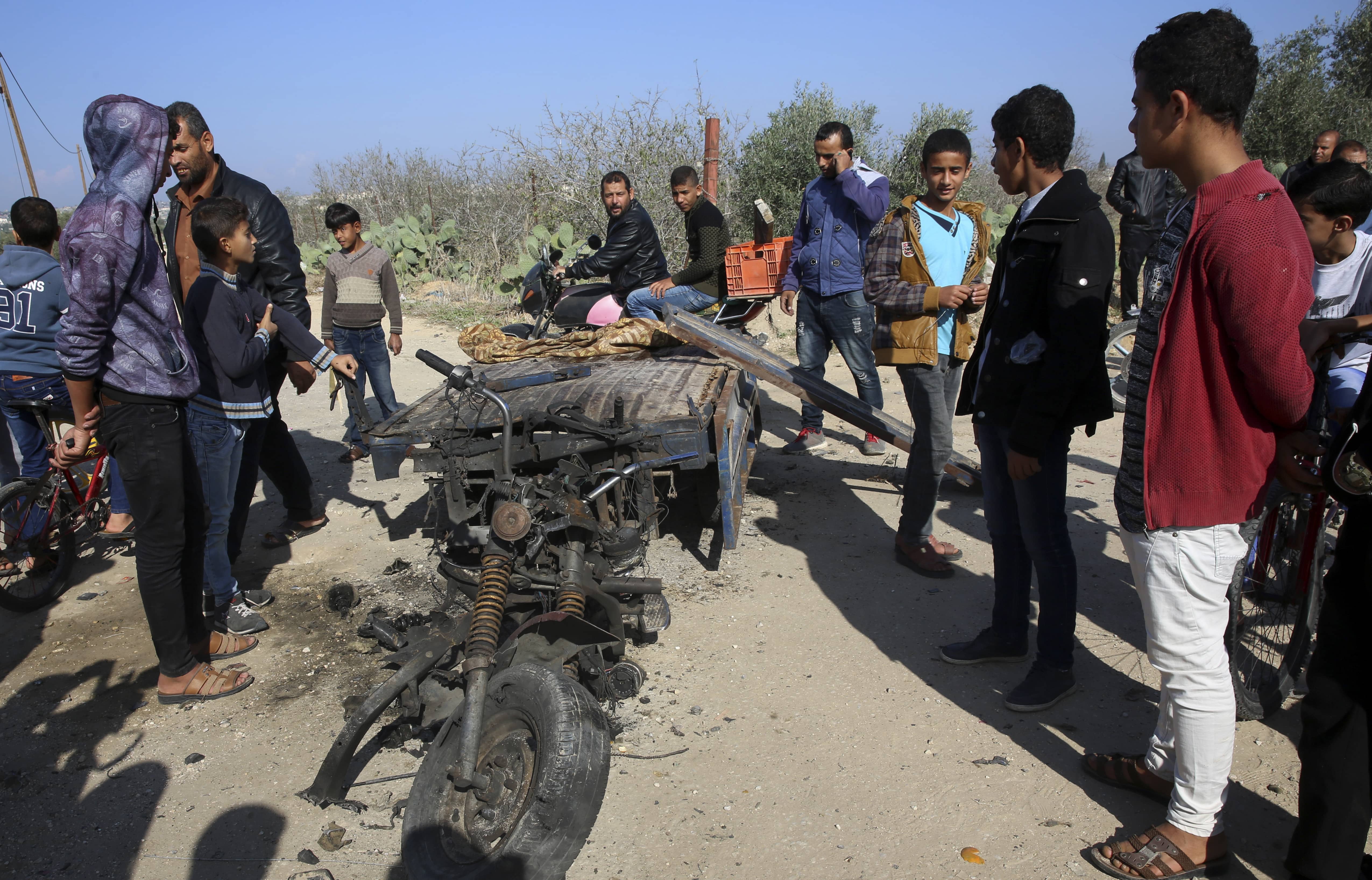 Photo of Palestinians inspecting a vehicle that was destroyed 