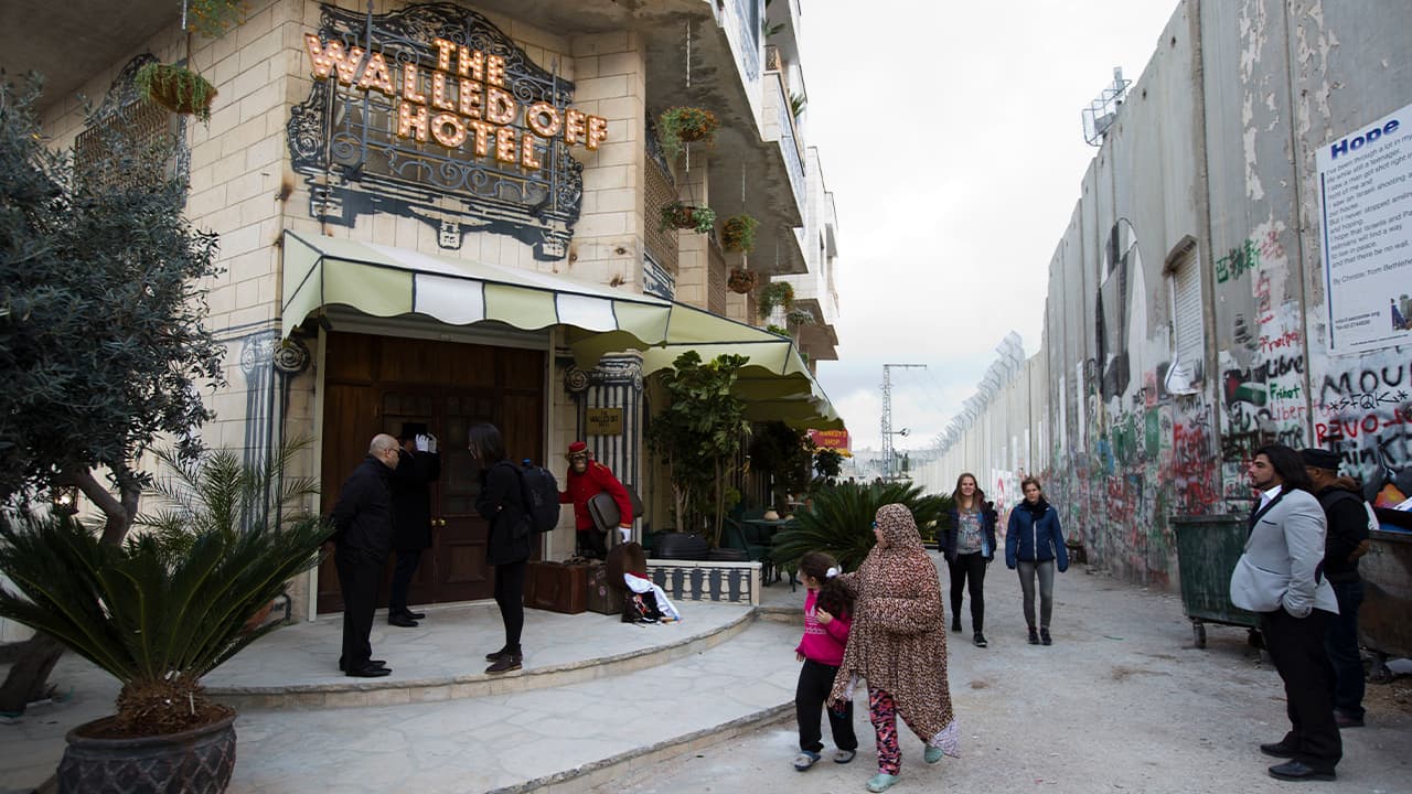Photo of people walking by "The Walled Off Hotel"