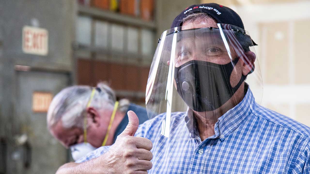 Photo of a man wearing a face shield that he made giving the thumbs-up sign