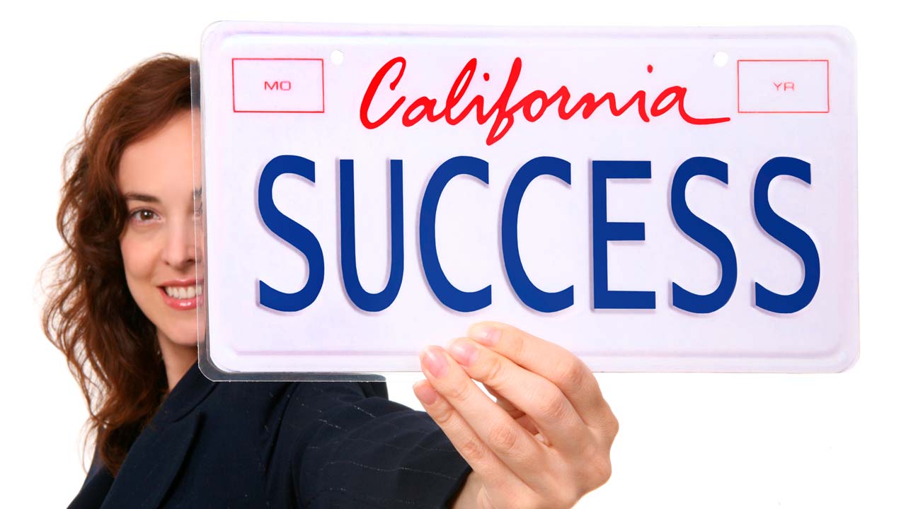 Photo of a woman holding a California license plate that says "Success"