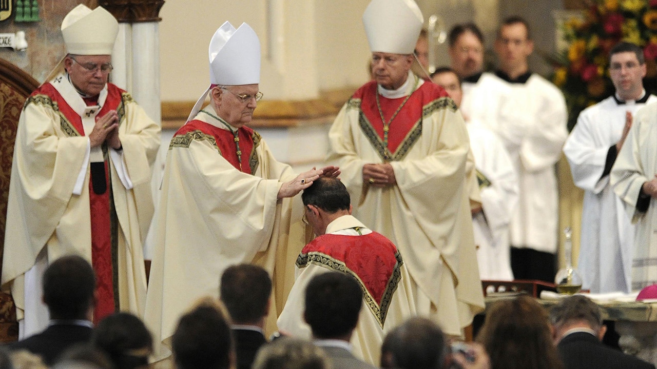 Photo of retiring bishop kneeling and praying