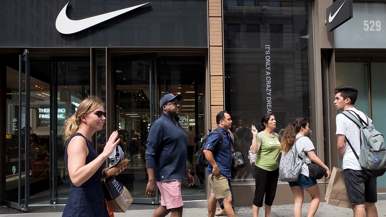 Photo of people passing in front of a Nike store in New York