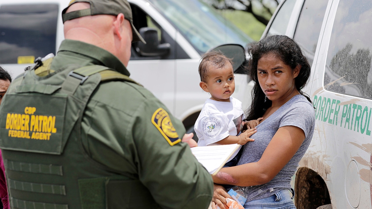 Photo of a mother and her child surrendering to U.S. Border Patrol agents