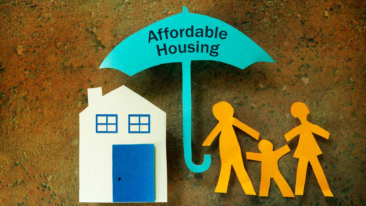 Image of a stick figure family, an umbrella with the words "affordable housing" and a small home