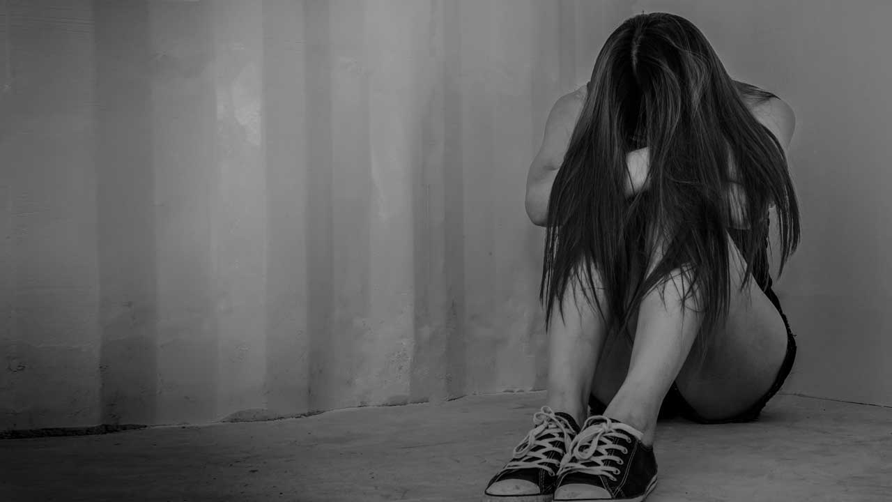 Photo of a sad young woman sitting in a room on the floor