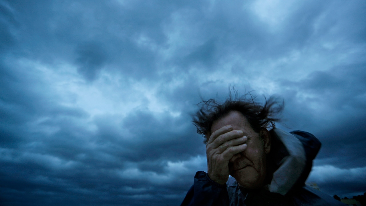 Photo of Russ Lewis covering his eyes from a gust of wind