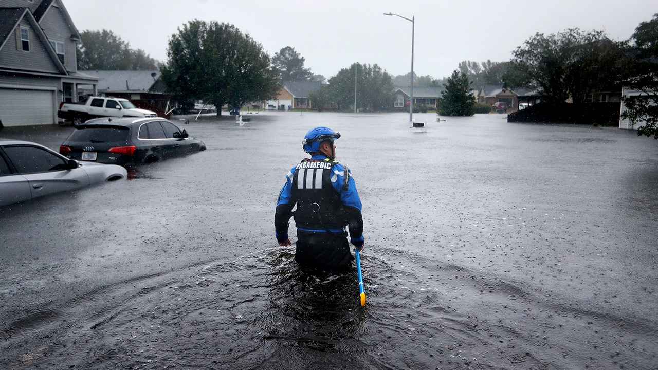 Photo of a member of the North Carolina Task Force search and rescue team wading through flooded neighborhoods
