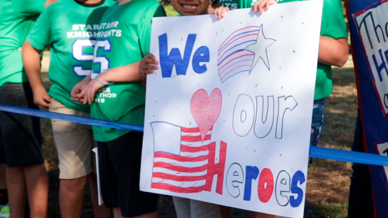 Photo of students holding a homemade sign saluting their heroes