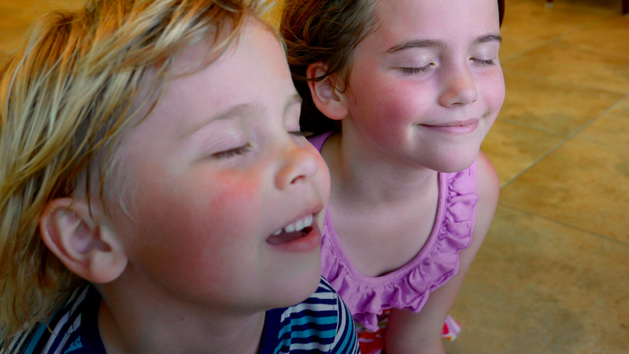 Young children cooling off in front of air conditioner.