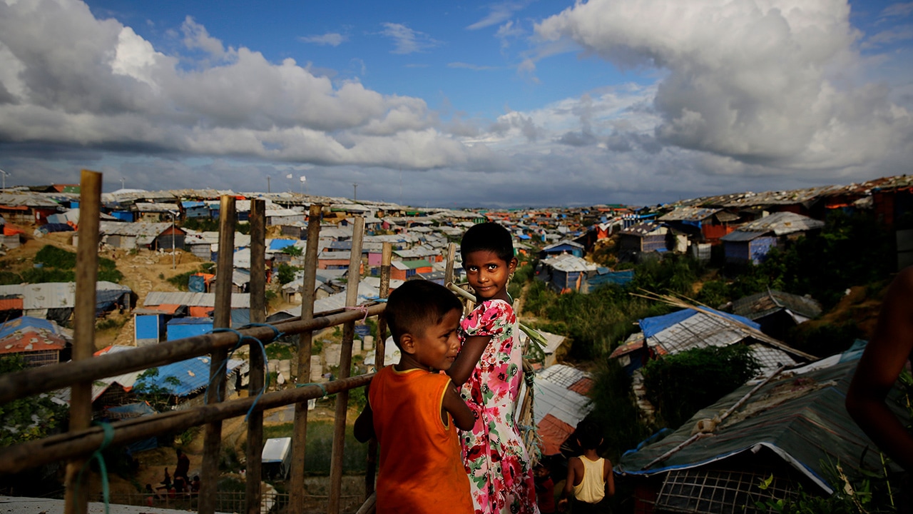 Rohingya children standing next to a bamboo fence
