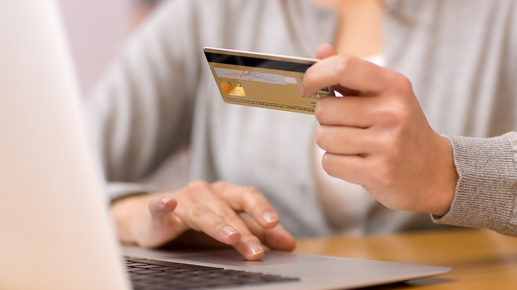 Online Sales - Woman makes credit card purchase using laptop computer