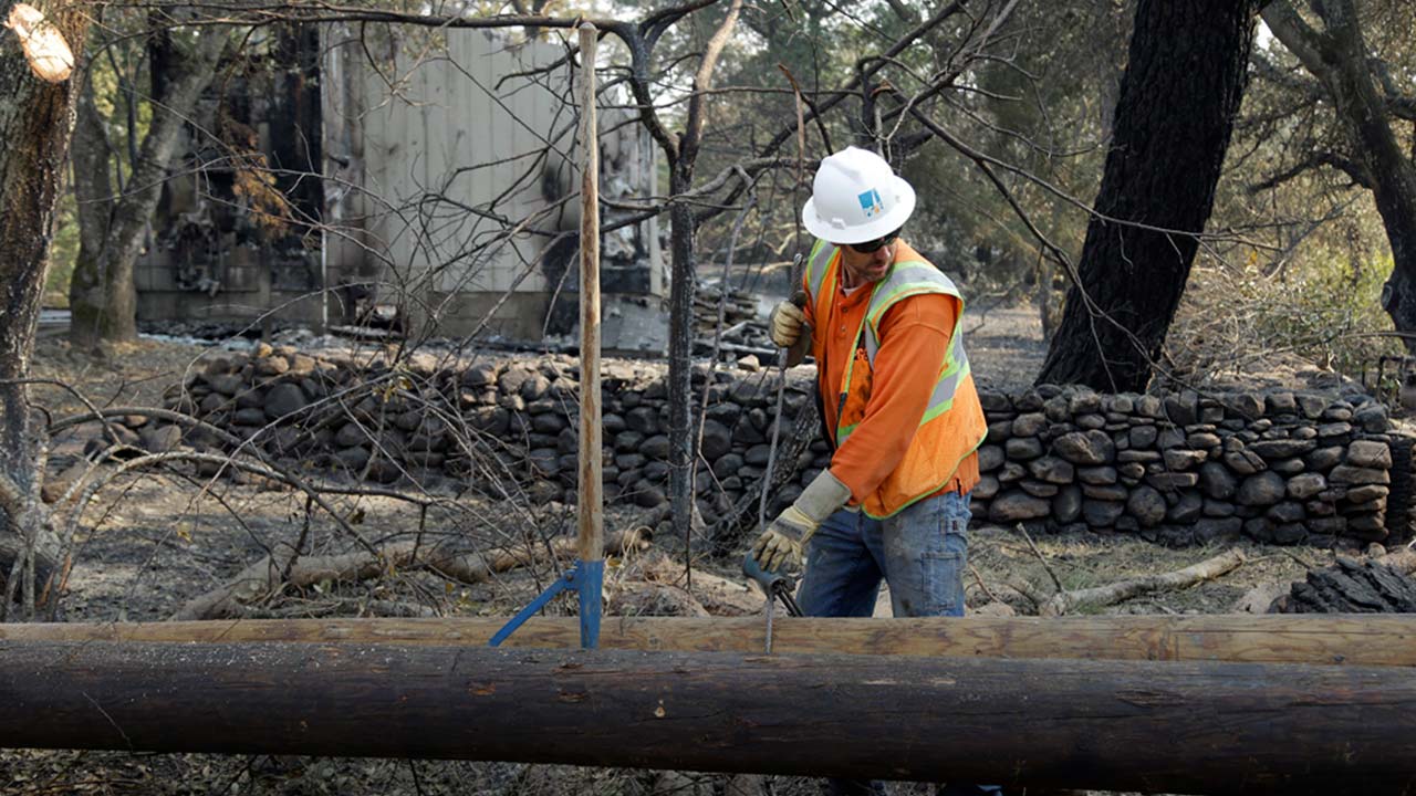 Photo of PG&E employee replacing power poles damaged by a wildfire