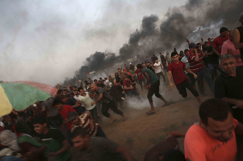 Photo of protesters running from tear gas at the Gaza Strip border