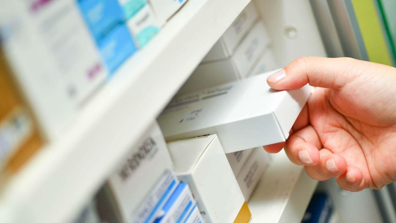 Photo of a pharmacist's hand holding a medicine box