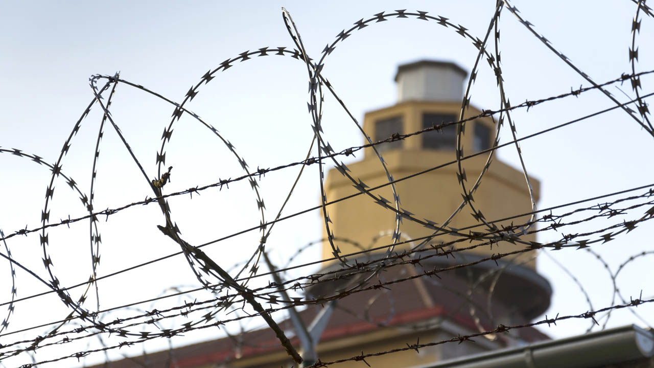 A prison guard tower viewed through razor wire fencing