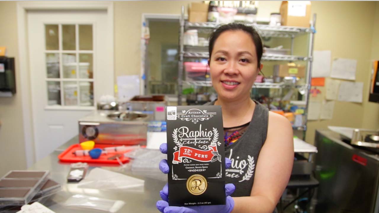 Owner of Raphio Chocolate Factory holds up a bag of chocolate