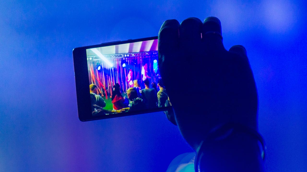 Photo of a parent videoing a school musical with a smart phone