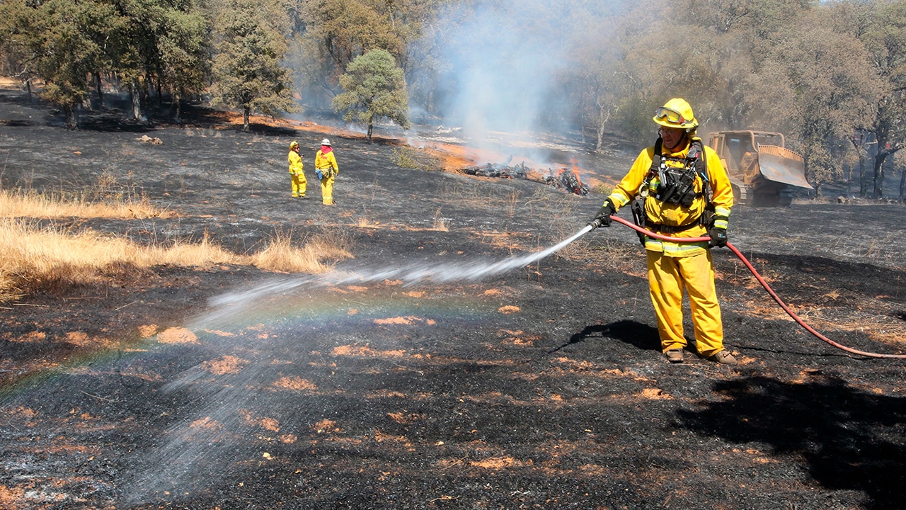 Photo of firefighters spreading water on smoldering spots