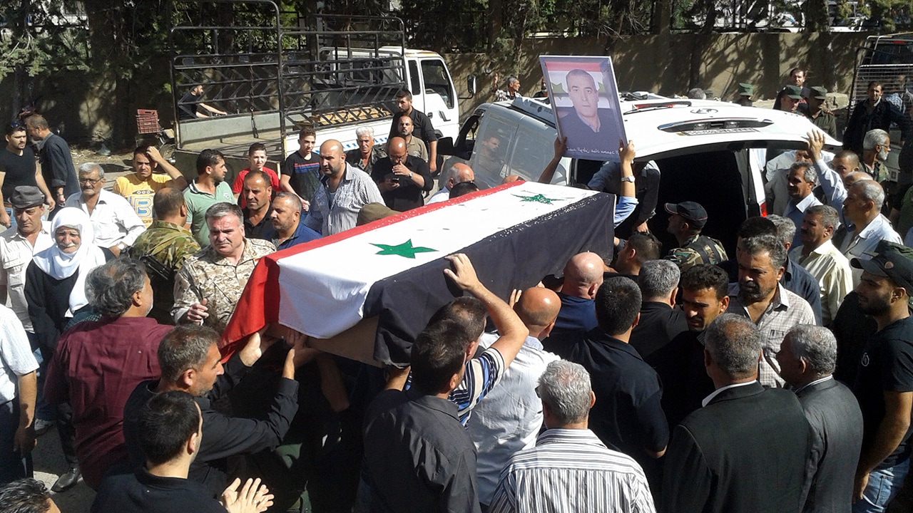 Photo of mourners carrying a coffin after IS attacks in Syria