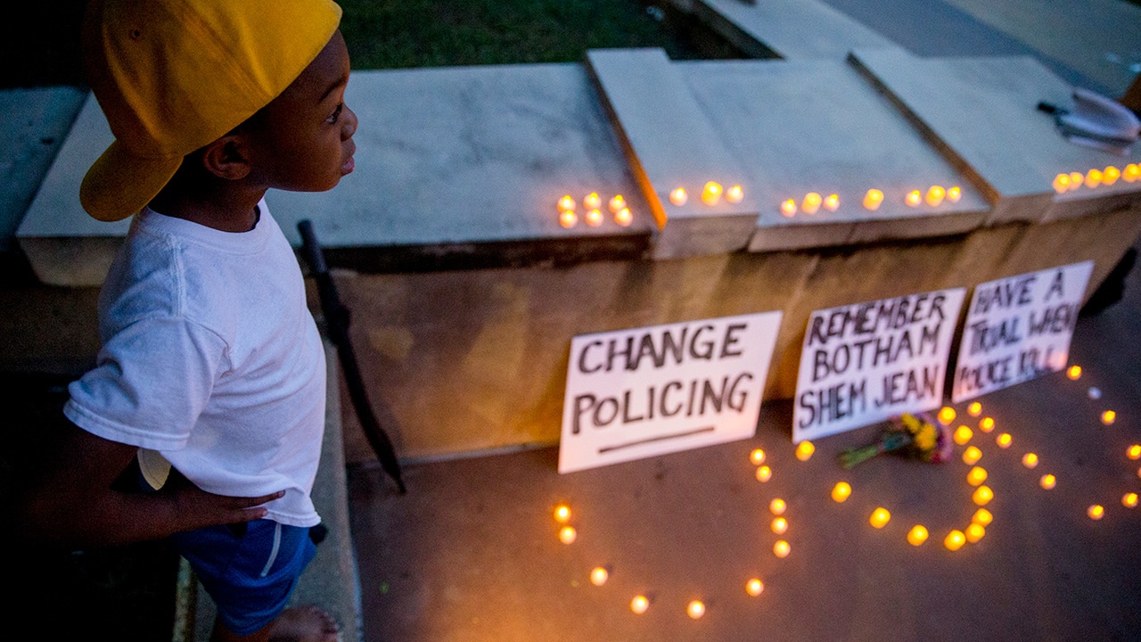 Photo of Solomon Grayson, 6, stands on a ledge next to a memorial