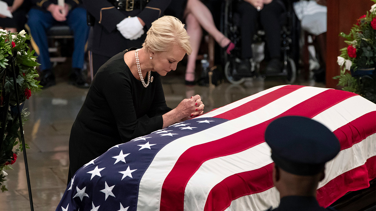 Photo of Cindy McCain leaning over John McCain's casket