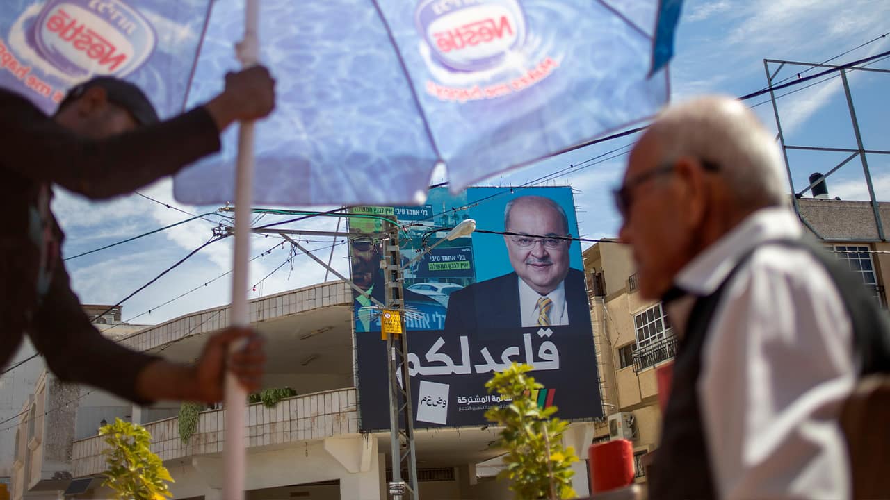 Photo of Israeli Arabs in a coffee shop near an election campaign poster showing Israeli Politician Ahmad Tibi of the Joint List in Tira, Israel