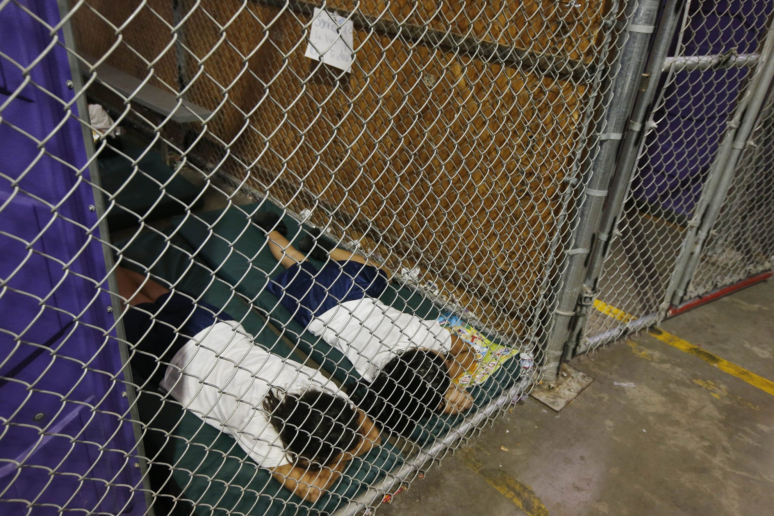 Two female detainees sleep in a holding cell,