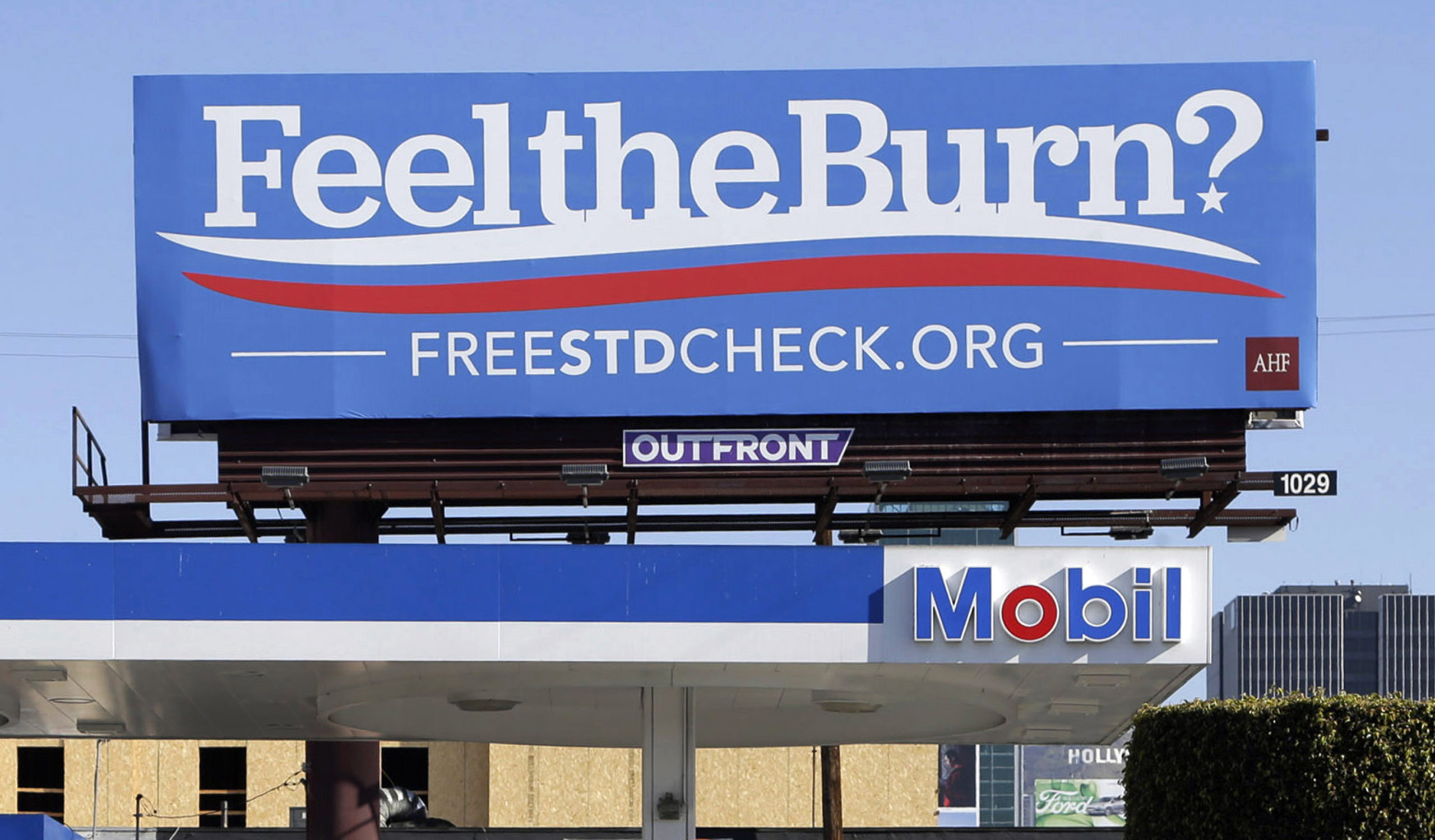 A billboard above a gas station that reads "Feel The Burn," actually promotes free STD testing.