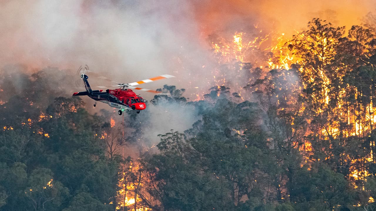 Photo of a helicopter and wildfires burning in Australia