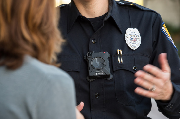 Photo of an officer with a body cam talking to a woman