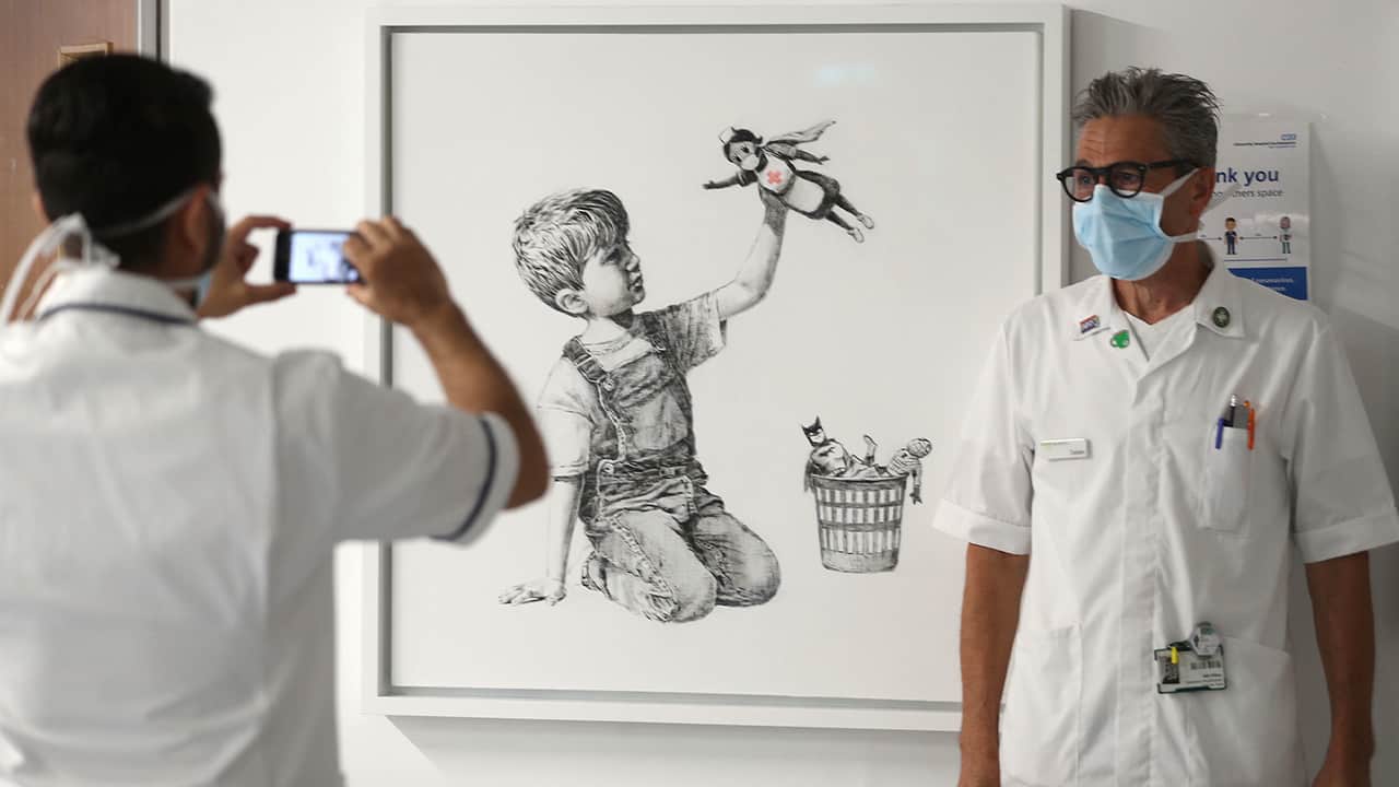 Photo of health care workers in front of a new artwork by Banksy