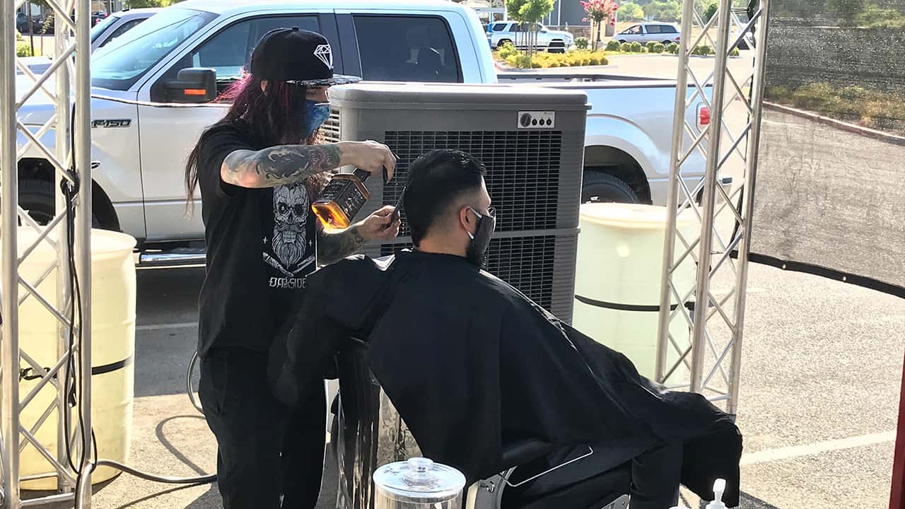 Picture of barber giving a haircut outdoors during California's ordered shutdown because of the coronavirus pandemic