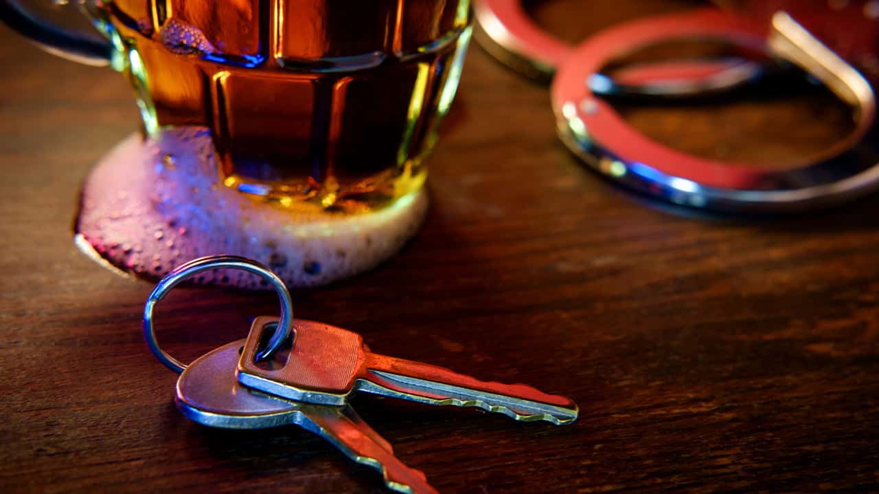 Image representing drunken driving: a beer glass, car keys, and handcuffs