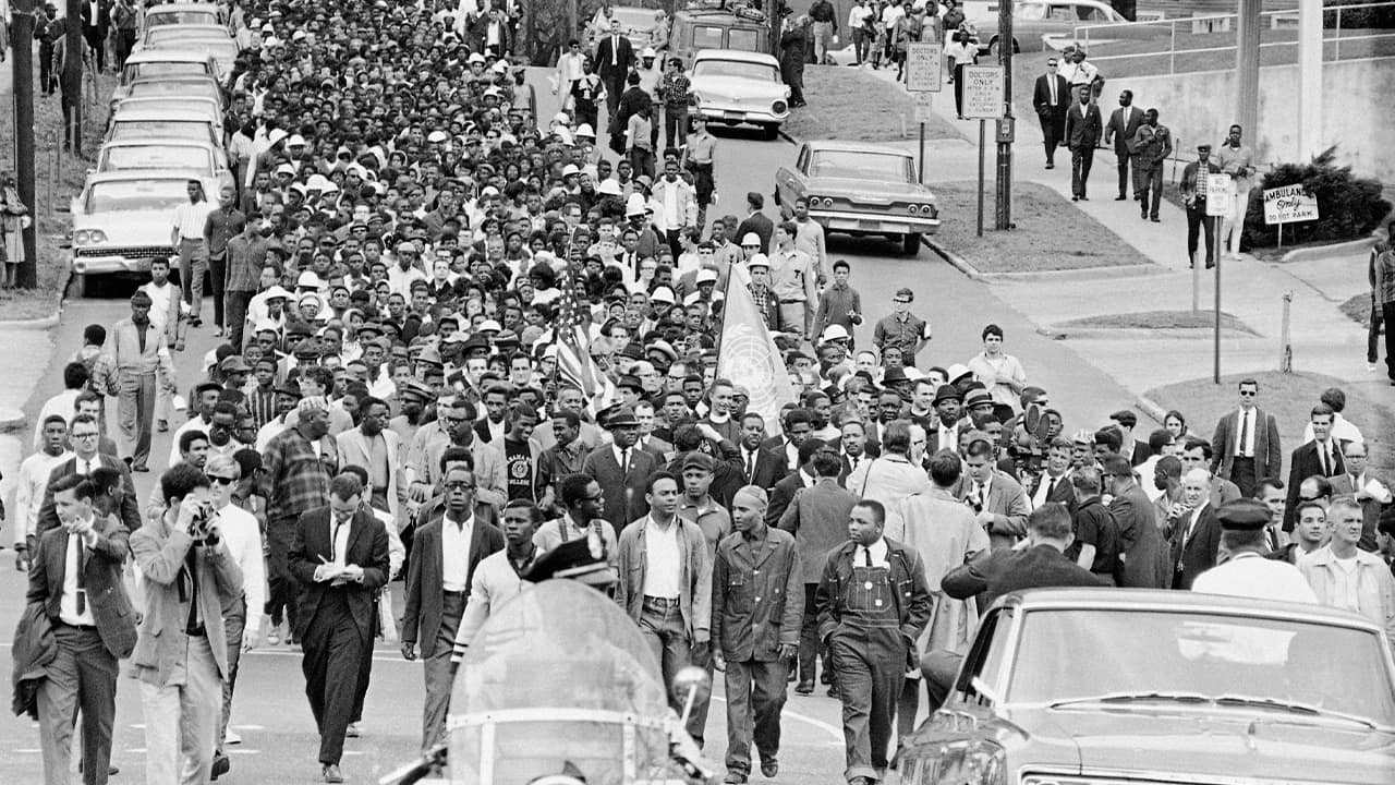 Photo of demonstrators walking to the courthouse behind the Rev. Martin Luther King Jr. in 1965