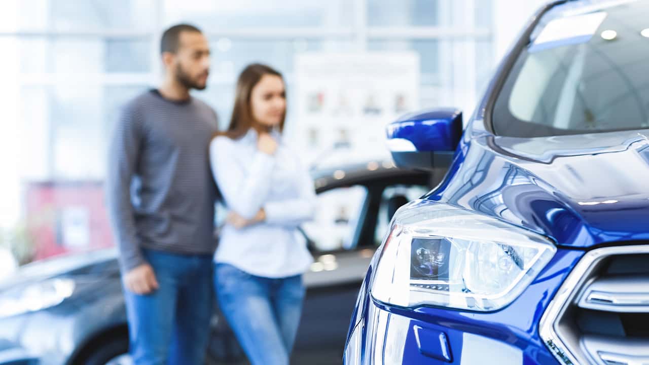 Photo of a man and woman shopping for a new car at a dealership