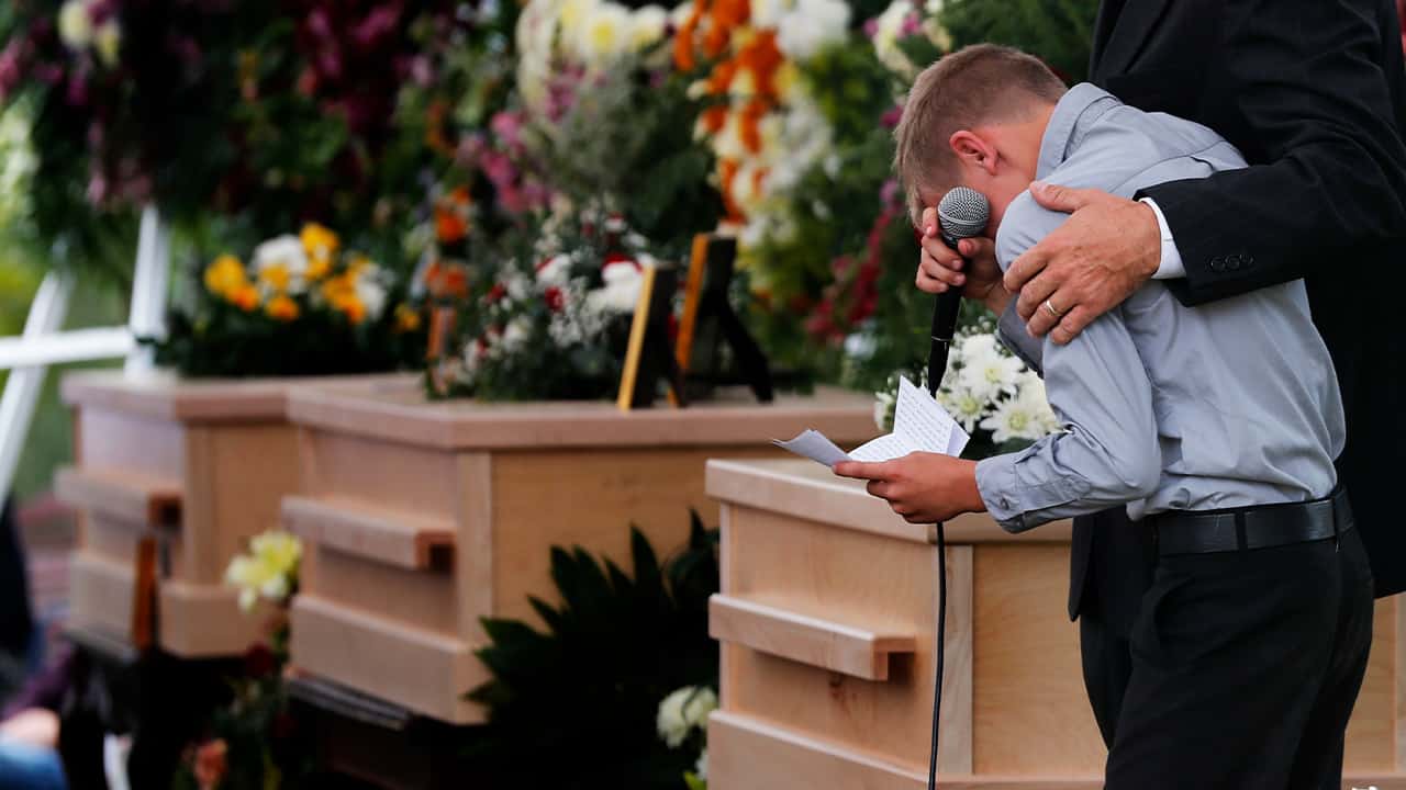A boy pauses as he speaks at a funeral 