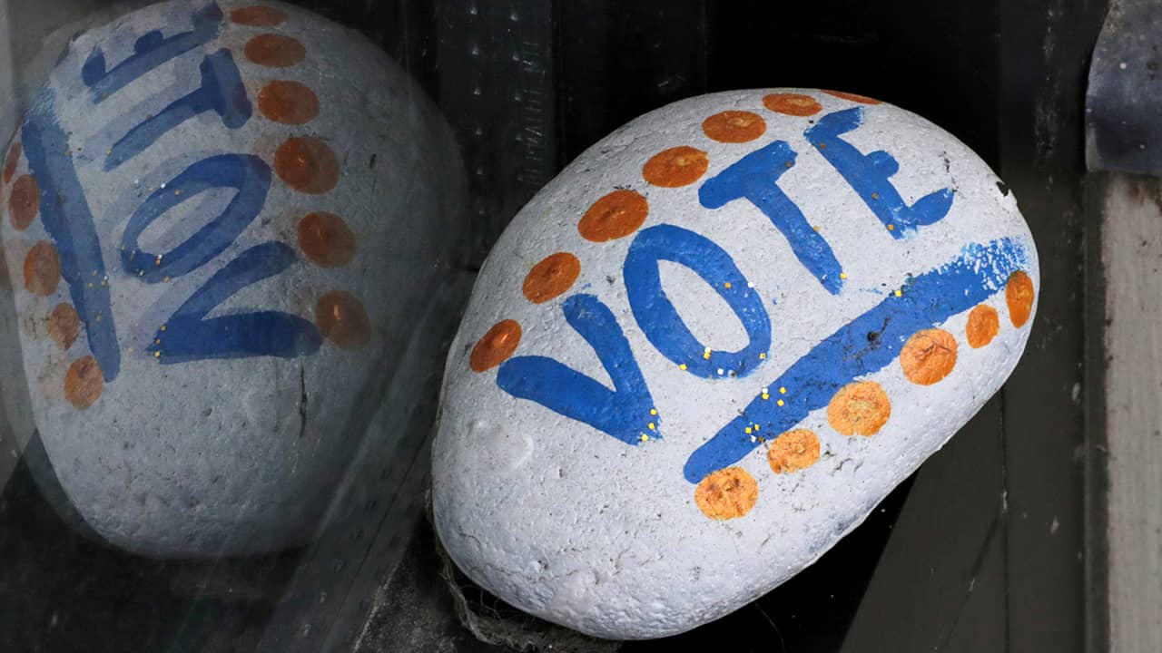 Photo of a stone painted with the word "VOTE" painted on it