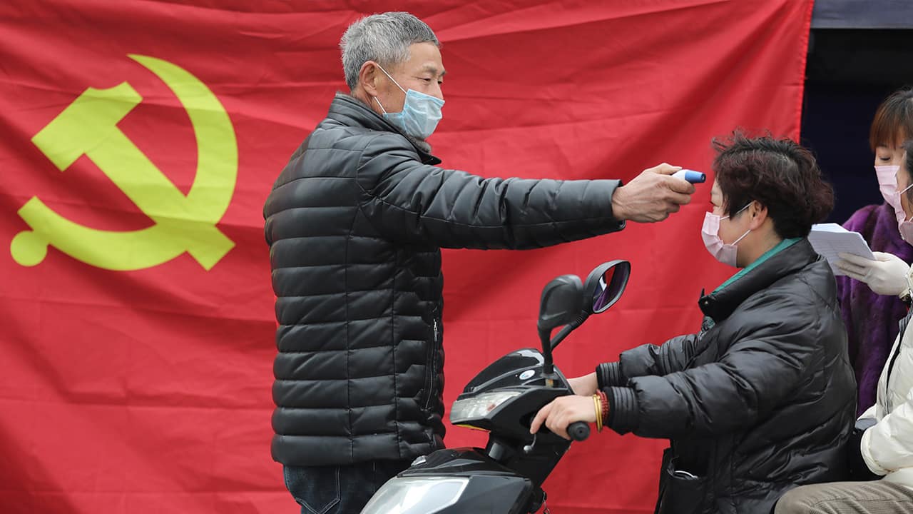 Photo of a volunteer taking the temperature of a scooter driver