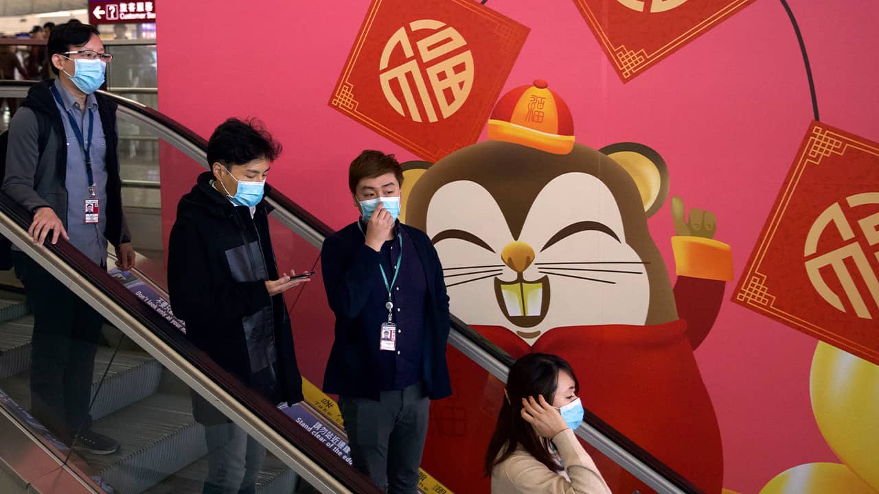 Photo of people wearing face masks as they ride an escalator in China
