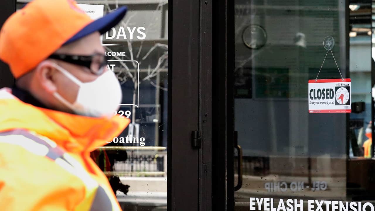 Photo of a man walking past a closed store 
