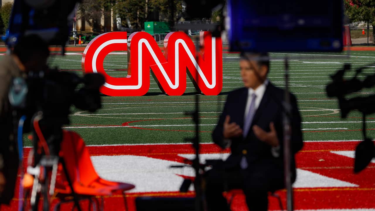 Photo of a journalist recording a video near a CNN sign