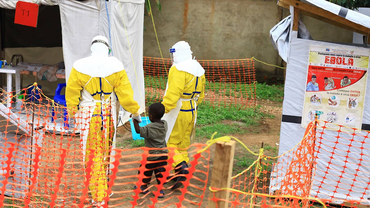 Photo of health workers walking with a boy that has ebola