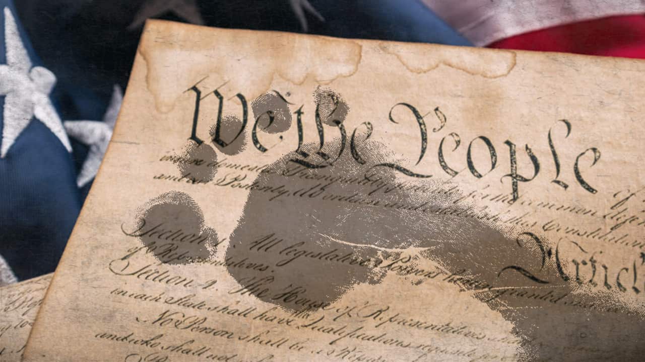 Composite photo of footprints trampling the U.S. Constitution