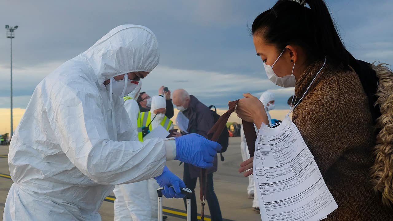Photo of a worker wearing a protective suit checking luggage 